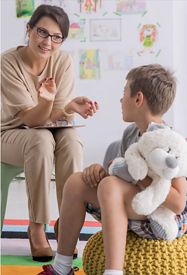 Educatore che lavora con un bambino a un tavolo con materiali didattici